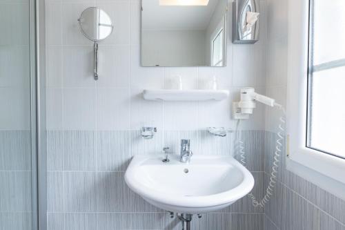 a white bathroom with a sink and a mirror at Hôtel Restaurant La Croix Verte Vich in Vich