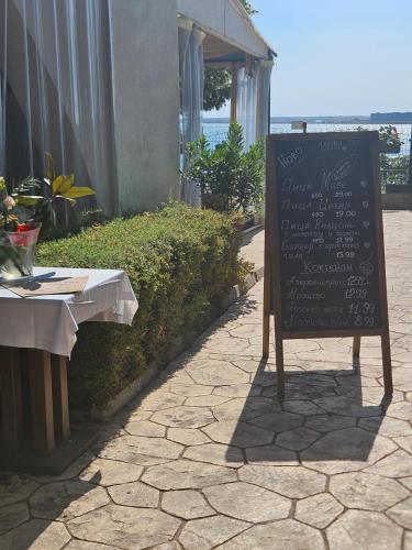 a chalkboard sign sitting on a sidewalk next to a table at Seaview Holiday - Черноморска почивка in Aheloy