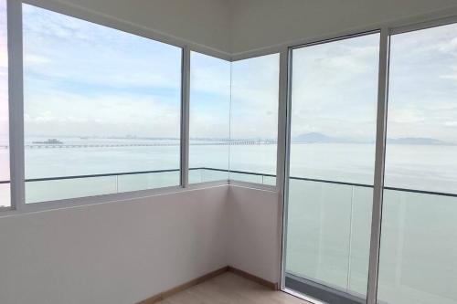 an empty room with glass windows with a view of the ocean at Penang Seaview Apartment up to 11 pax in Bayan Lepas