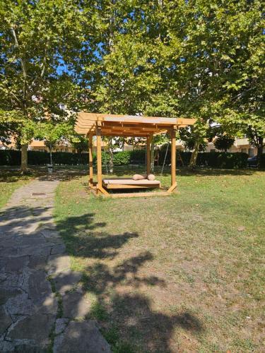 a wooden bench sitting in a park under a tree at Seaview Holiday - Черноморска почивка in Aheloy