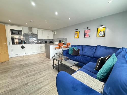 a living room with a blue couch and a kitchen at RNM - Business Professionals Stay, Walsall City Centre, 2 Bedroom with ensuite and bathroom, Entire Place, Kitchen & Washroom with amenities, Smart Tv, Easy Access, Fast WiFi, Parking Nearby, Great transport links in Walsall