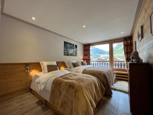 une chambre avec deux lits et une grande fenêtre dans l'établissement Appartement moderne avec balcon, WiFi et cuisine équipée - FR-1-694-168, à Val dʼIsère