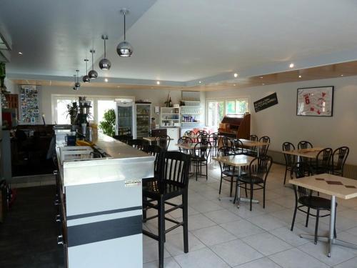 um restaurante com mesas e cadeiras e uma cozinha com um bar em Le Pidanoux em Saint-Julien-du-Verdon