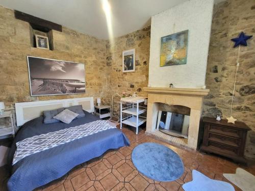 une chambre avec un lit et une cheminée dans l'établissement Gîte de la Marquise, Maison périgourdine en pierre à 2 min à pieds de la cité médiévale de Sarlat, à Sarlat-la-Canéda