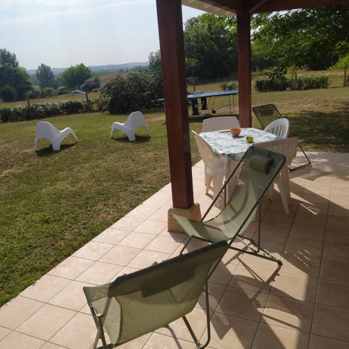 a patio with a table and chairs on the grass at Gîte du Couchant à Fleurance dans le Gers en occitanie in Fleurance