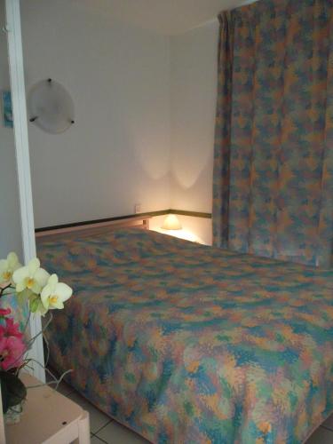 - une chambre avec un lit et une table fleurie dans l'établissement Le Hameau de l'Ocean, à Saint-Hilaire-de-Riez