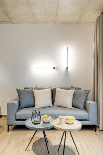 a living room with a blue couch and two tables at Amphora Nafplio- elegance Suites Apartmenthouse in Nafplio