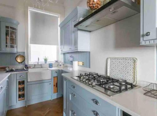 a kitchen with blue cabinets and a stove top oven at Breathtaking Walpole Sea Views in Margate