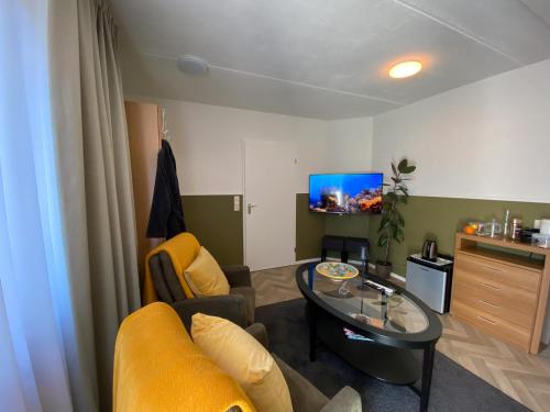 a living room with a yellow couch and a glass table at La Nuova Casa del Campo (vh De Kamp) in Dinxperlo