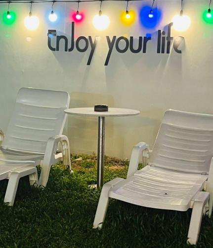 two chairs and a table and a table and a sign at Pupae Pool Villa Jomtien Pattaya in Jomtien Beach