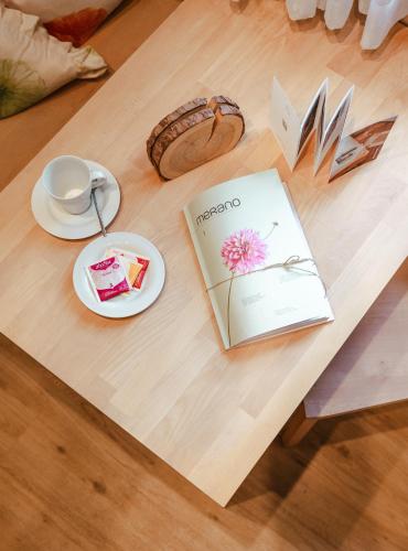 a table with a book and a plate on it at Hotel Villa Freiheim in Merano
