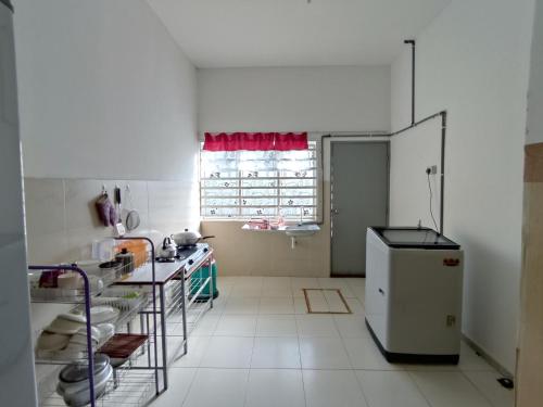a white kitchen with a refrigerator and a window at Homestay NAQ D' Kuala Kangsar in Kuala Kangsar