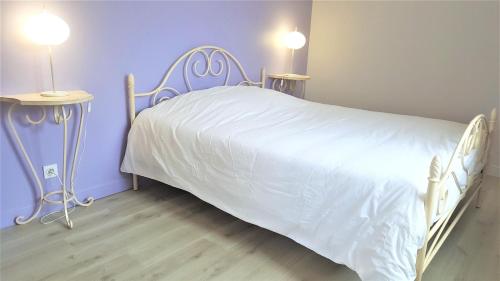 a bedroom with a white bed with purple walls at Gite 12 personnes in Digny