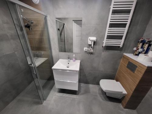 a bathroom with a sink and a shower and a toilet at Apartamenty Kacper Grzybowo in Grzybowo