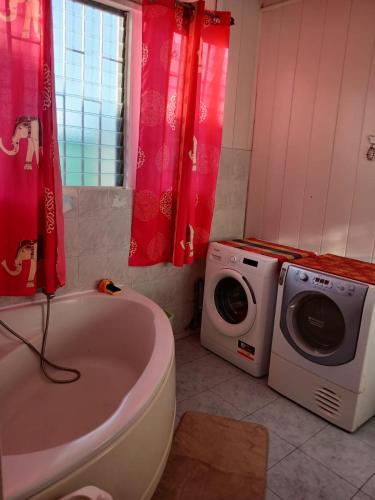 a bathroom with a tub and a washing machine at Grande Maison atypique proche du Maïdo in Saint-Paul