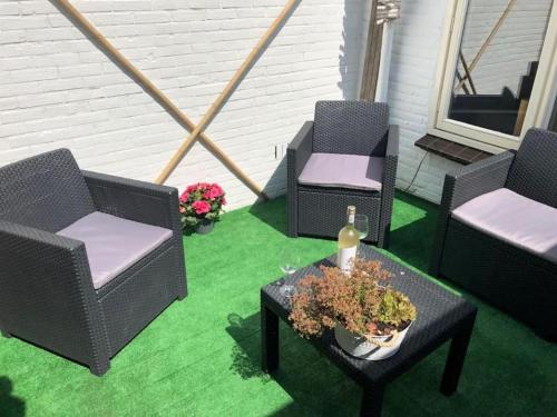 a patio with three chairs and a table with a bottle of wine at Vakantiehuisje aan Zee - 100m van Strand in Egmond aan Zee