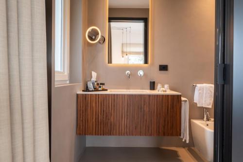 a bathroom with a tub and a sink and a mirror at Essenza Relais Contemporaneo in Cisternino