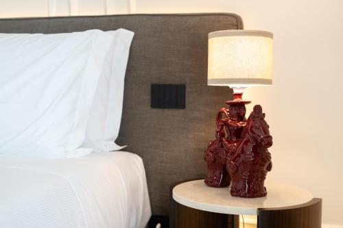 a red lamp sitting on a table next to a bed at Essenza Relais Contemporaneo in Cisternino