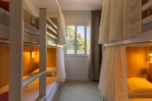 a bedroom with two bunk beds and a window at Corsica Hostel Porto-Vecchio, partie dortoirs in Porto-Vecchio