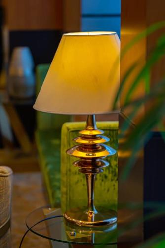 a glass lamp sitting on a glass table with a shade at Al Muhaidb Palastine - Jeddah in Jeddah