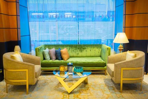 a living room with a green couch and two chairs at Al Muhaidb Palastine - Jeddah in Jeddah