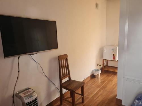 a television hanging on a wall with a wooden chair at Willa Hala in Vinhedo