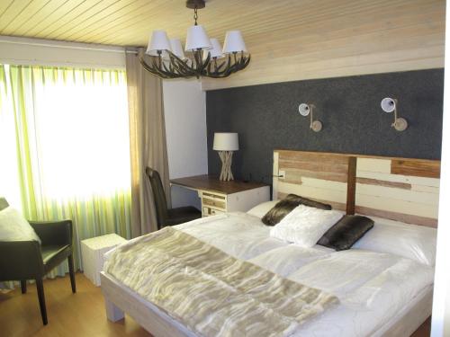 a bedroom with a large white bed and a desk at Hotel du Lac in Crans-Montana