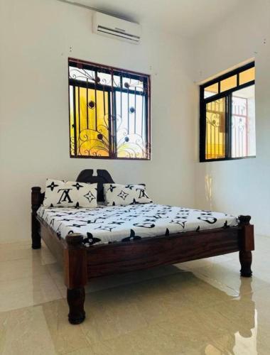 a bed in a room with two windows at paje zanzibar apartment in Paje