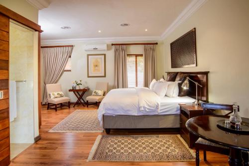 a hotel room with a bed and a desk and a room at Leaves Lodge and Spa in Nelspruit