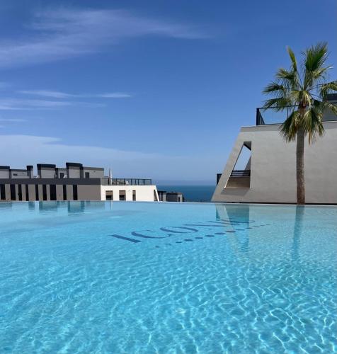 a swimming pool with a palm tree and a building at Iconic Alluba Alicante luxury bay in Gran Alacant