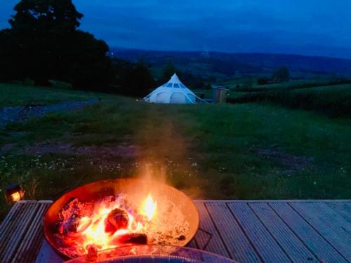a bonfire on a table with a tent in the background at Luxury Stargazing Glamping - Seren Aur with Hot Tub in Llanidloes