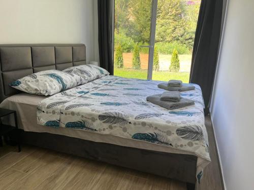 a bed with a quilt and pillows and a window at HARIZMA LUX Banja Vrujci in Popadić