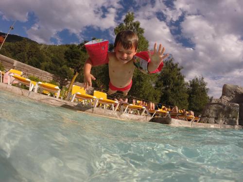 a young man jumping into the water at a pool at Apartaments Giberga in LʼAldosa
