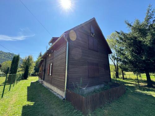 a wooden house with a fence in the grass at Mountain Cabin Retreat - Terrace, BBQ, Hot Tub in Lunca Bradului