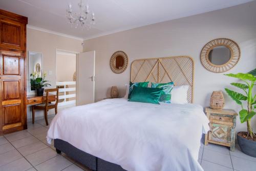 a bedroom with a large white bed and a desk at Leaves Lodge and Spa in Nelspruit