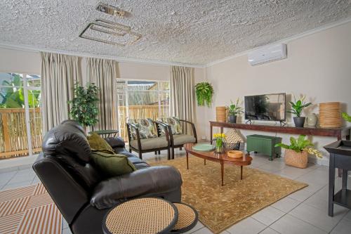 a living room with a leather couch and a tv at Leaves Lodge and Spa in Nelspruit