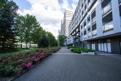 a brick walkway in front of a building with pink flowers at Apartamenty City Tower od WroclawApartament-pl in Wrocław