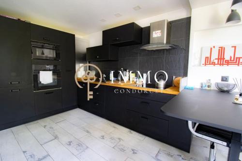 une cuisine avec des armoires noires et un comptoir dans l'établissement Aux portes de Paris, à LʼHay-les-Roses