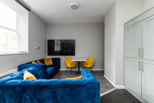 a living room with a blue couch and yellow chairs at NE1 City Studios & Apartments in Newcastle upon Tyne