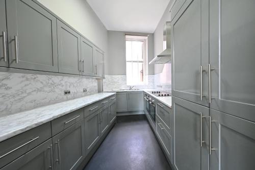a white kitchen with white cabinets and a window at NE1 City Studios & Apartments in Newcastle upon Tyne