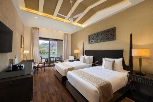 a hotel room with two beds and a table and chairs at Essentia Luxury Resort & Spa Udaipur in Udaipur