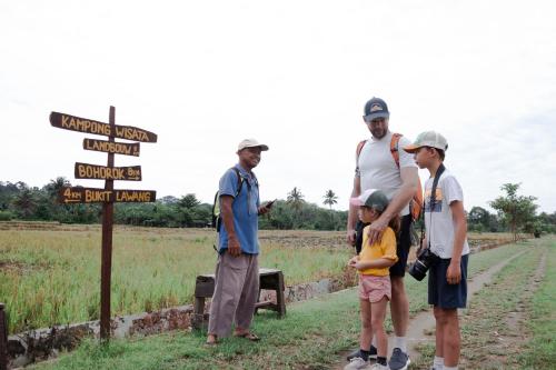 a group of people standing next to a street sign at AMBOW Homestay Jungle Trekking & Village Tour in Bukit Lawang