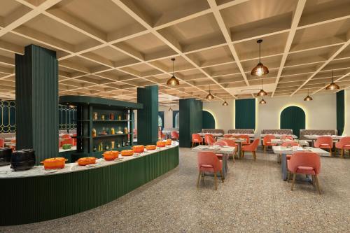 a dining room with tables and chairs and green walls at Essentia Luxury Resort & Spa Udaipur in Udaipur