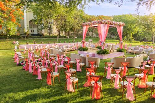 a long table with chairs and a table with an arch at Essentia Luxury Resort & Spa Udaipur in Udaipur
