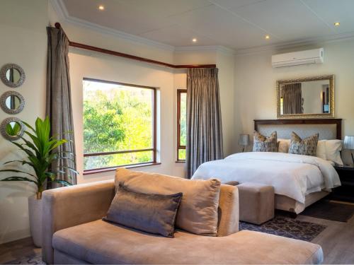 a bedroom with a large bed and a couch at Leaves Lodge and Spa in Nelspruit