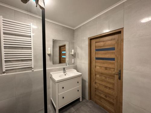 a bathroom with a sink and a wooden door at Hotel Echo in Cedzyna