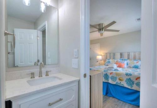 a bathroom with a sink and a bed at Dune Alright in Oak Island