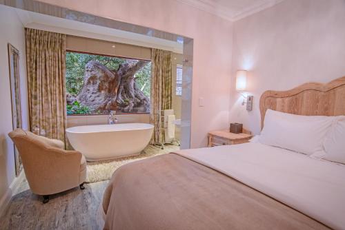 a bedroom with a bed and a tub and a tree at Leaves Lodge and Spa in Nelspruit
