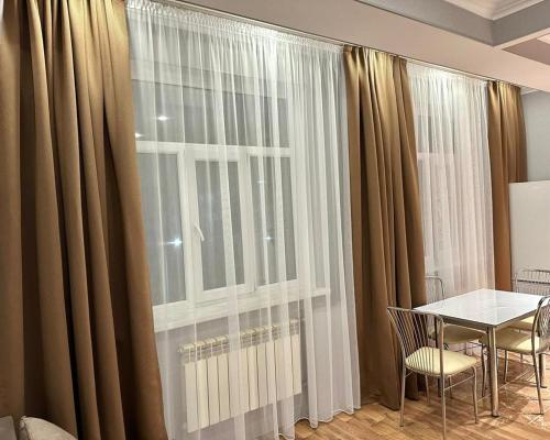 une salle à manger avec une table et une grande fenêtre dans l'établissement Green Park Однокомнатная, à Aktau