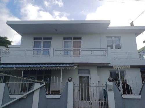 a white house with a balcony and a fence at Appartement avec terasse in Bel Air